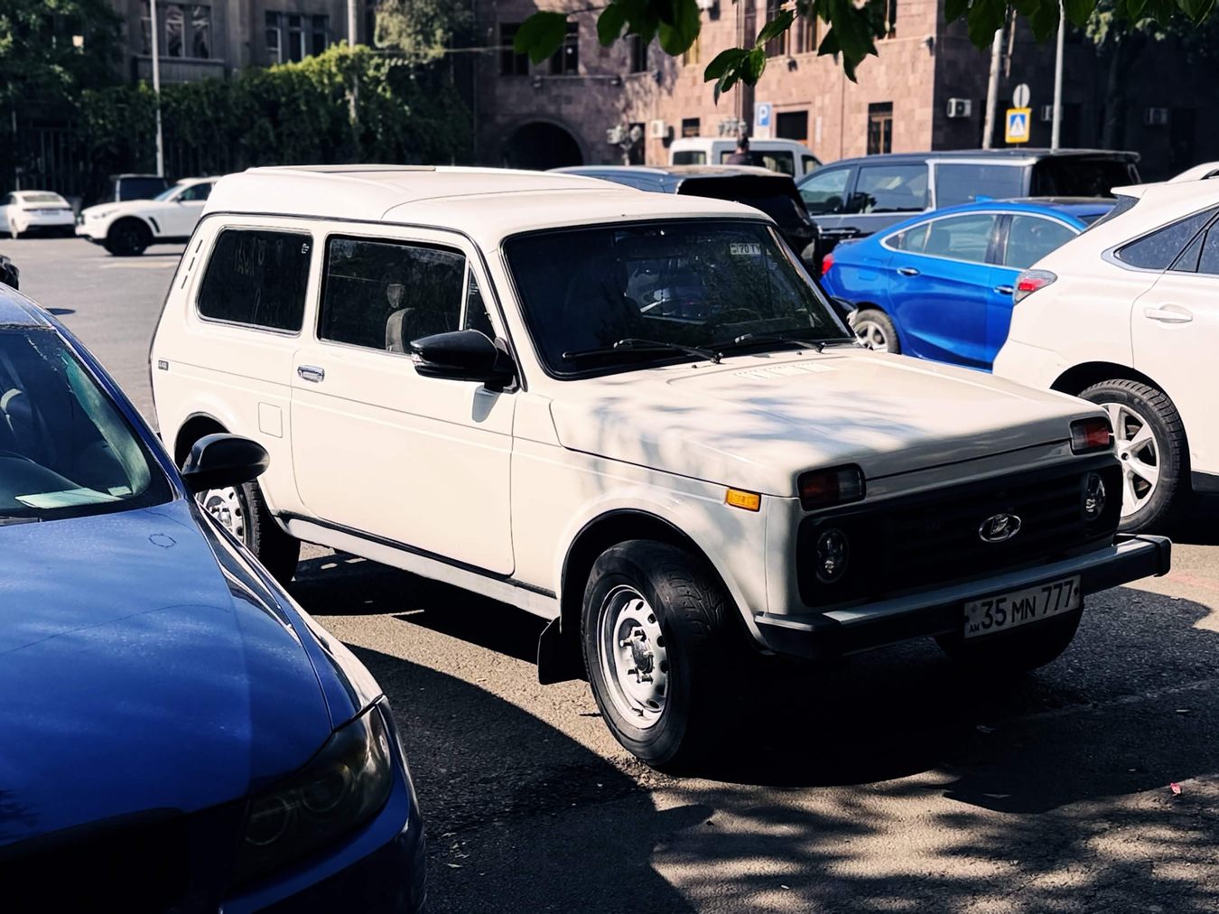 停在葉里溫街邊的白色 Lada Niva 三門四驅車，方正車身、蚌殼式引擎蓋，水箱罩上有 Lada 的帆船廠徽